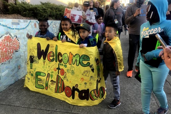 Four children hold up a yellow banner sign that reads 