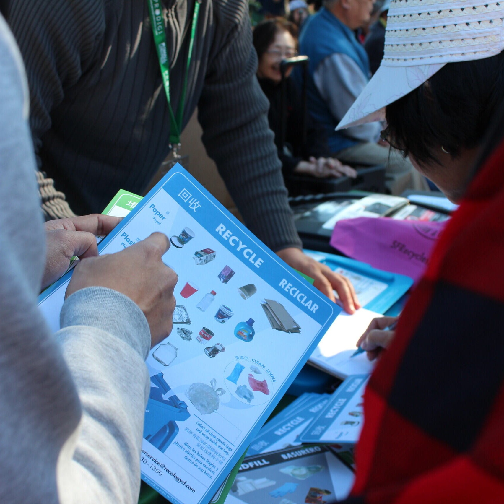 Outreach SFE staff explains to a community member about recycles that belong int he blue bin