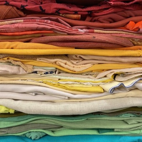 Donated textiles arranged by color like a rainbow